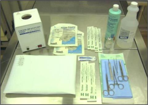 Medical setup on a metal table featuring a STERILIZER 500 unit, RADI-TOUCH surgical gloves, antiseptic solution bottles, packaged syringes and scalpels, and surgical instruments including scissors and forceps arranged on a blue cloth.